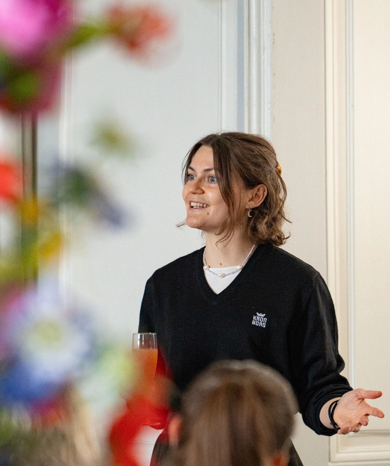 Kronborg-guide taler engageret og holder et glas ved afternoon tea-arrangement – nærfoto af formidlingsdelen af oplevelsen
