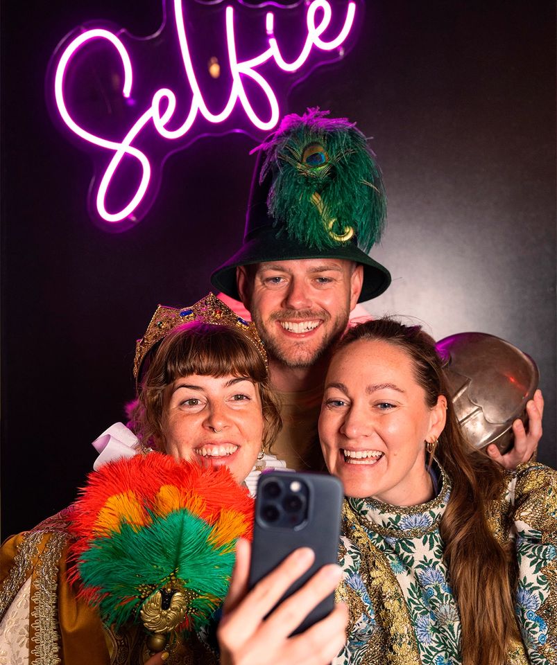 Tre personer i kostumer tager festlig selfie.