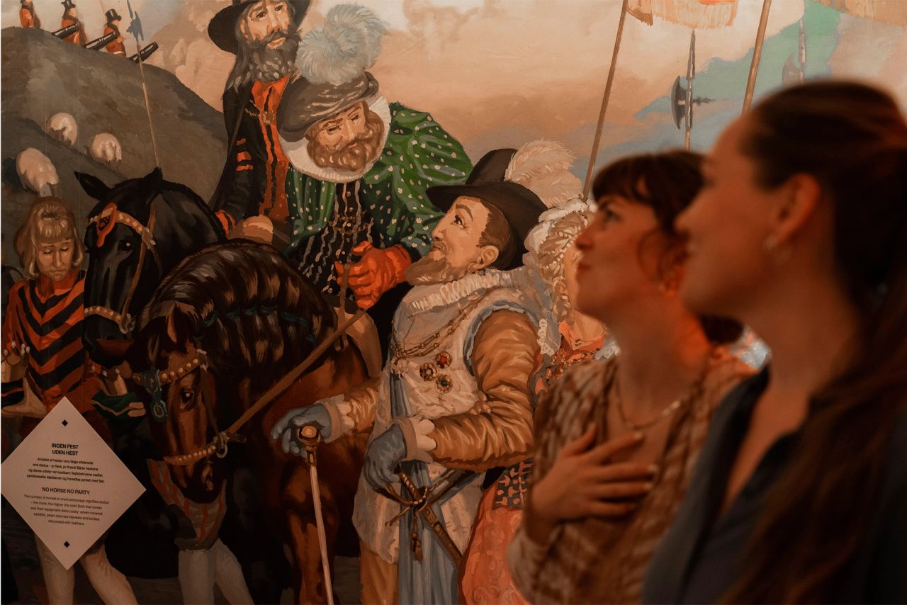 To kvinder ser på et historisk maleri i et museum
