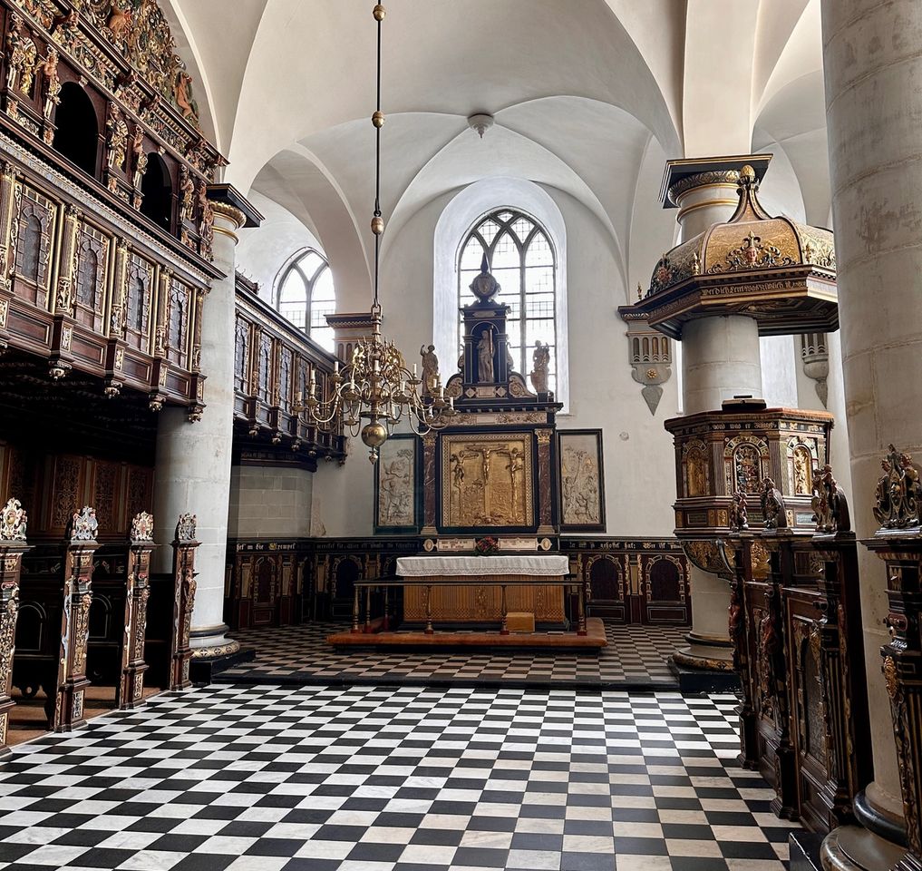 Kronborgs slotskirke med sort-hvid skakternet gulv, udskårede trækorgelpladser, hvælvet hvidt loft og forgyldt altertavle